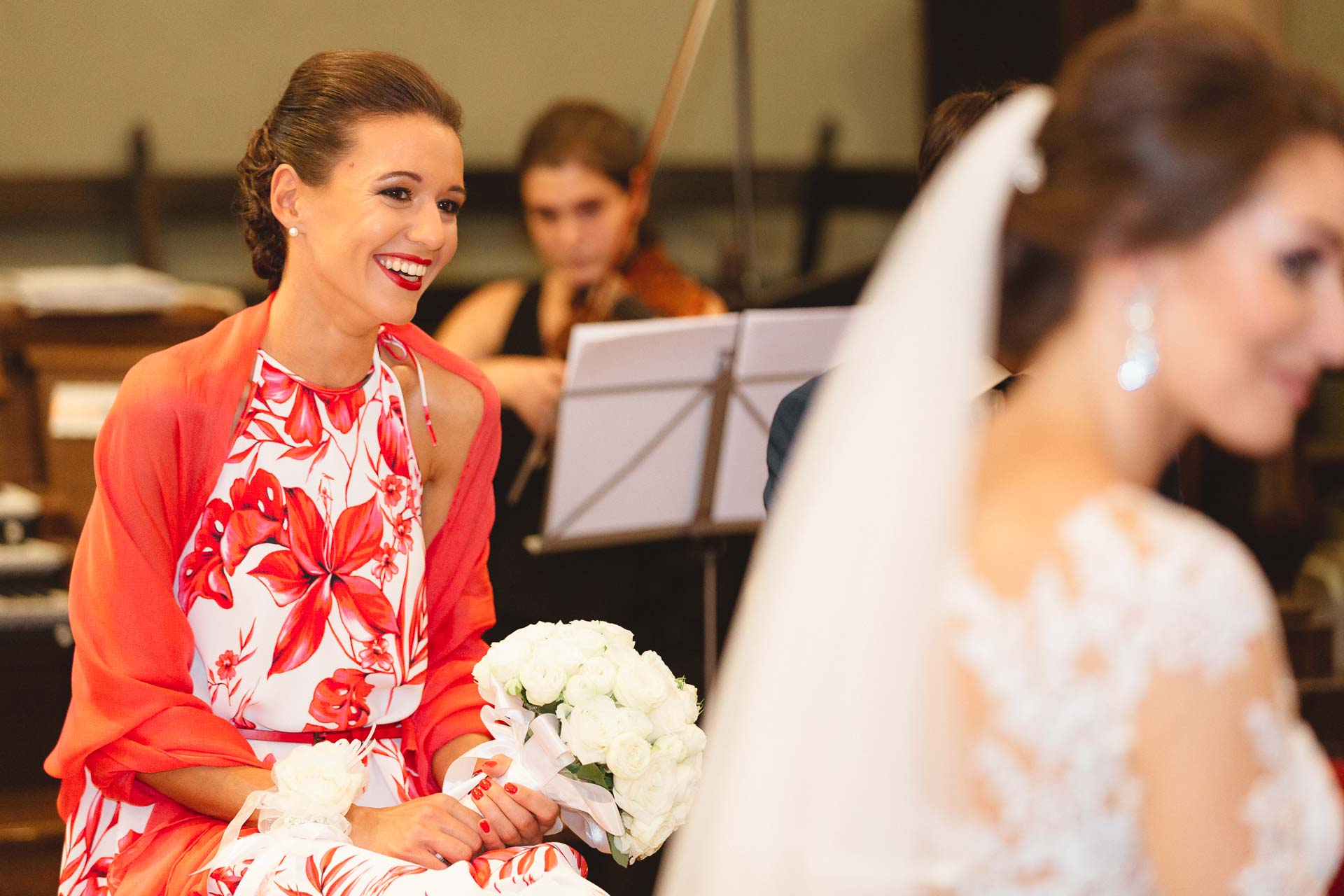 L'amica in abito a fiori sorride, con la violinista sullo sfondo