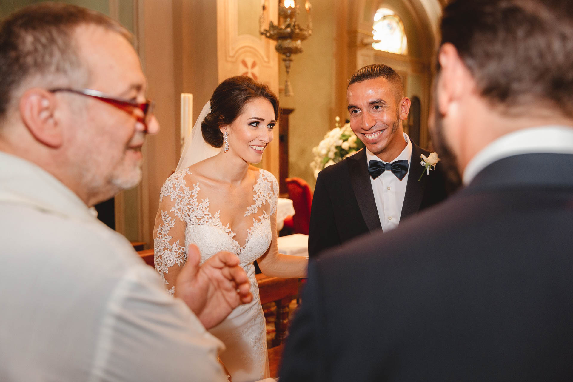 Gli sposi salutano il sacerdote e un amico in papillon
