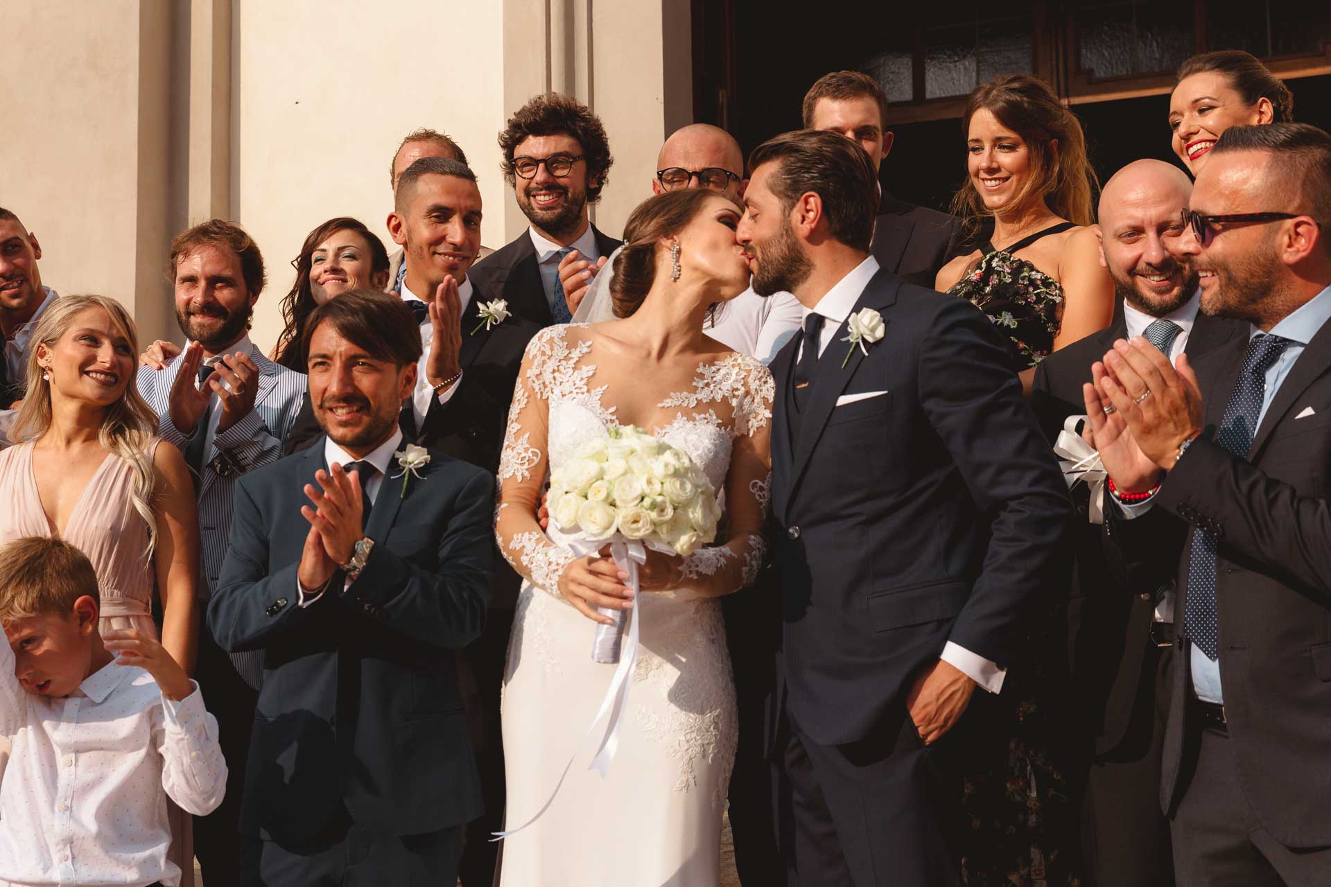Il bacio degli sposi tra gli amici che applaudono