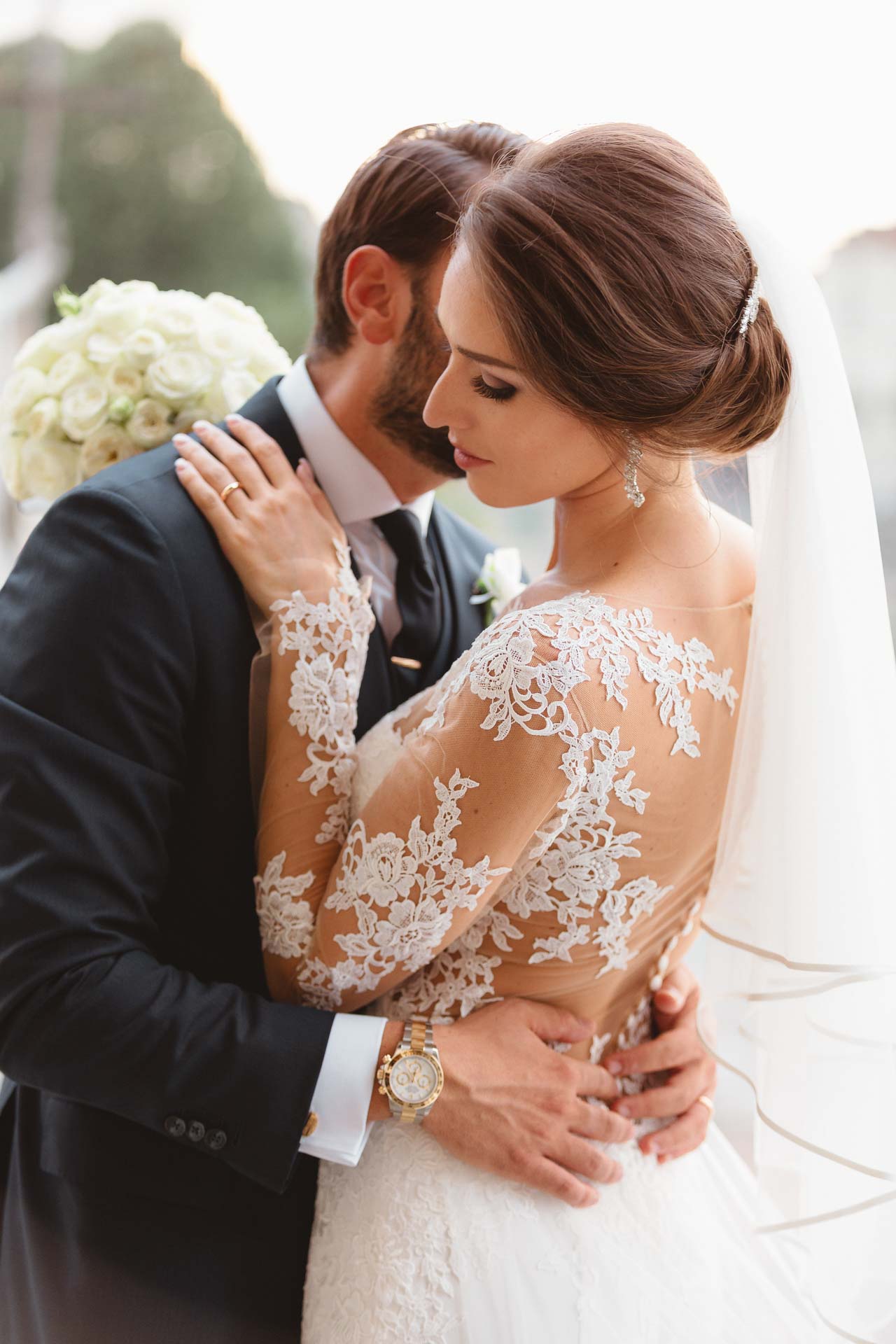 Lo sposo abbraccia la sposa, la mano sul pizzo della schiena