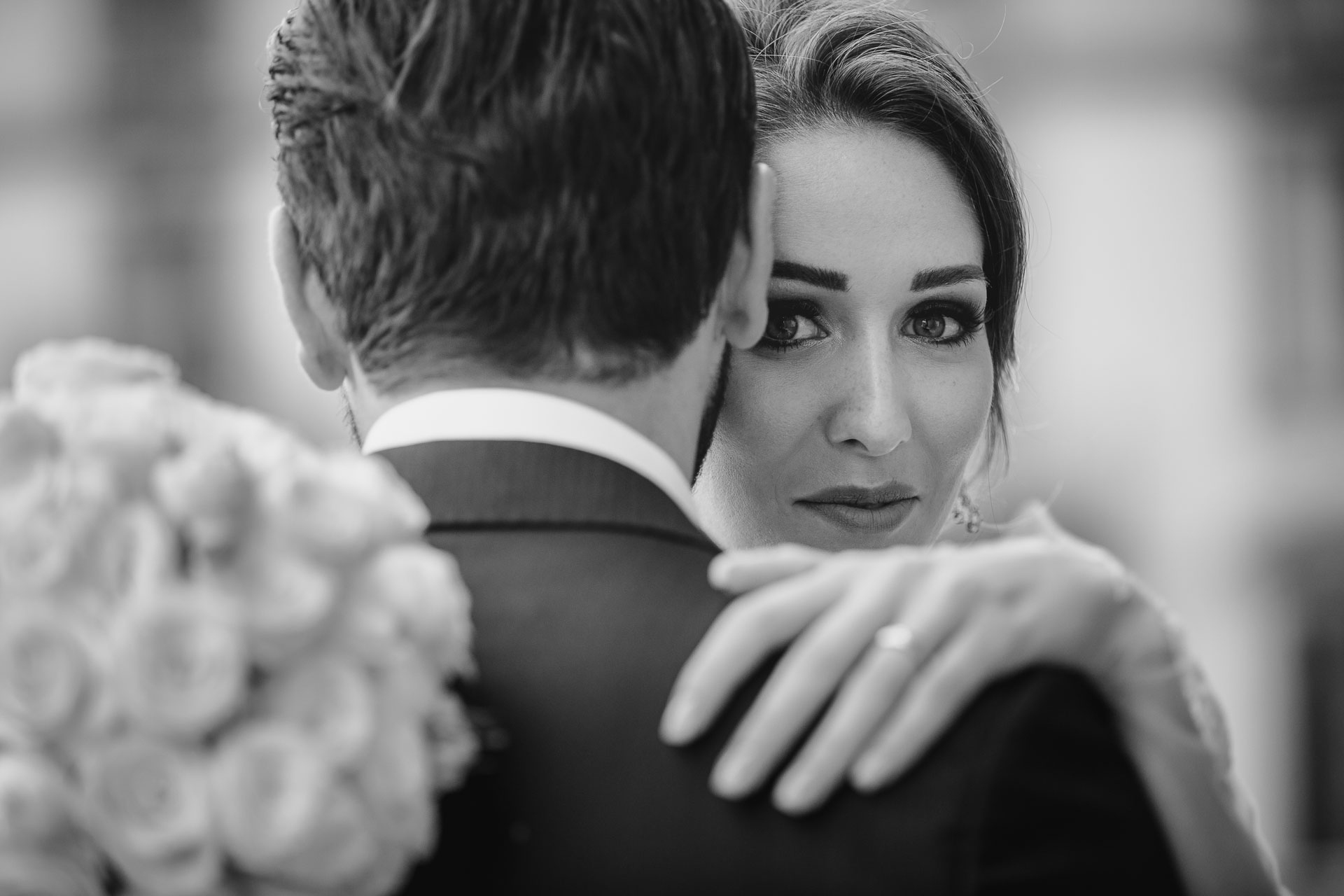 In bianco e nero, lo sguardo della sposa oltre la spalla dello sposo