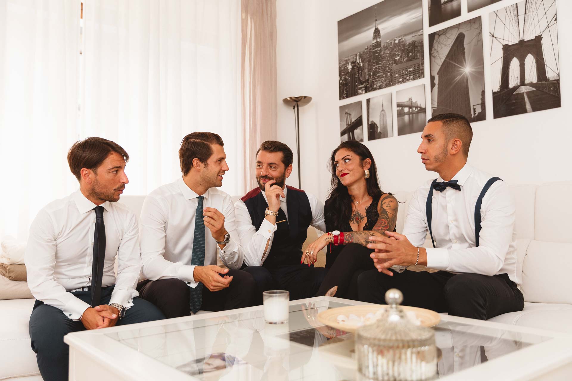 Gli amici e un'amica sul divano, sotto le foto di New York