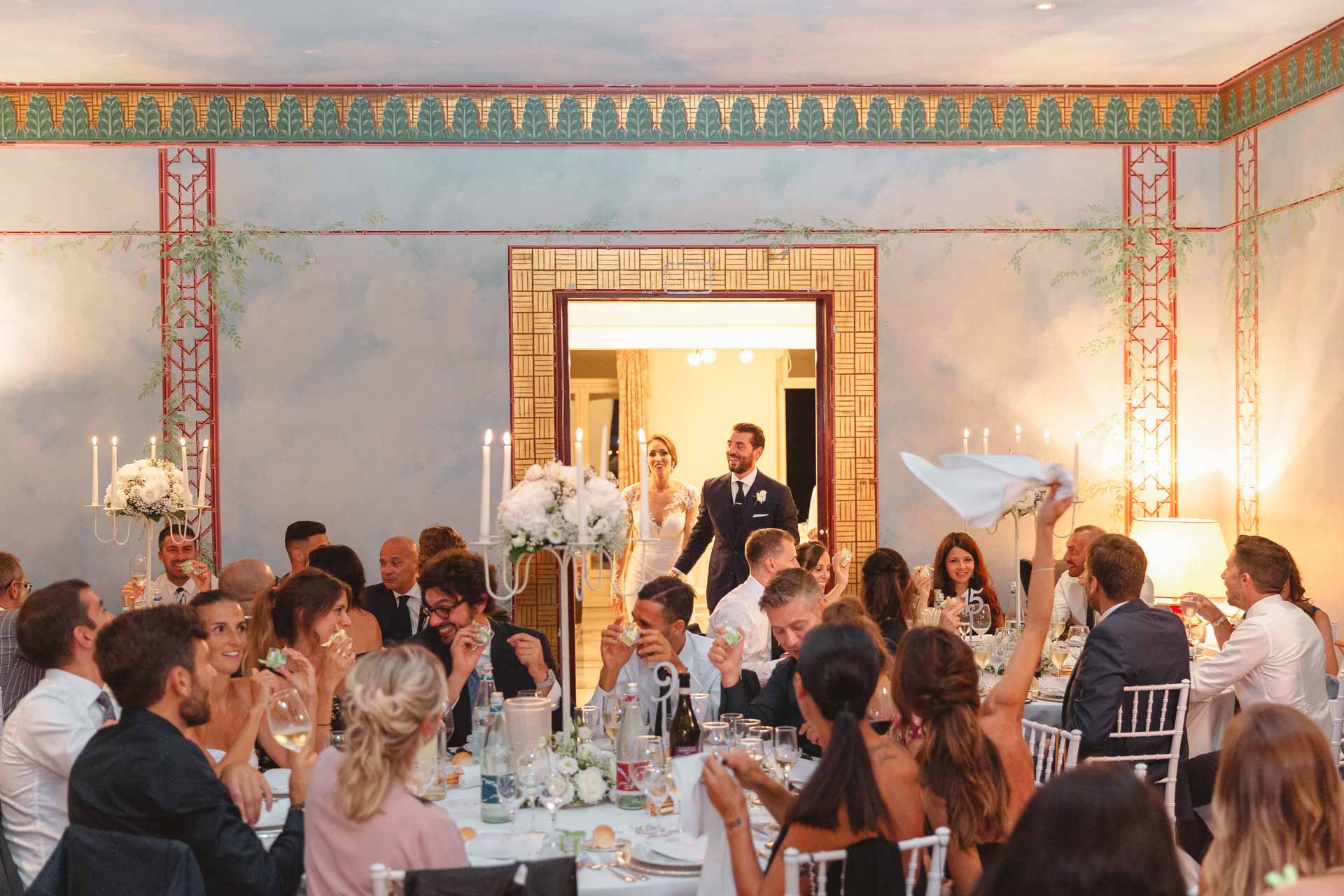 Gli sposi entrano in sala tra gli invitati che sventolano i tovaglioli