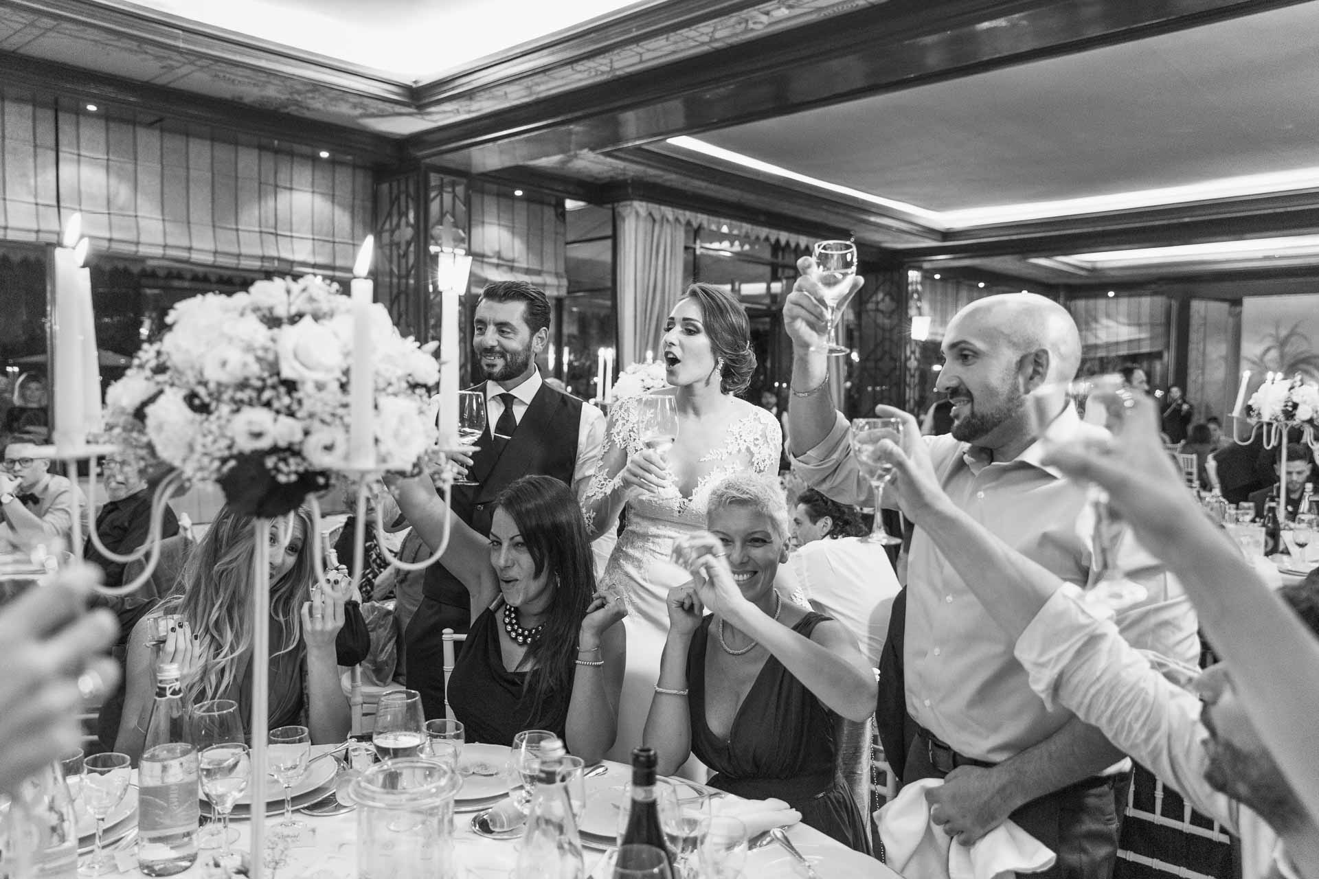 In bianco e nero, il brindisi degli invitati intorno alla sposa