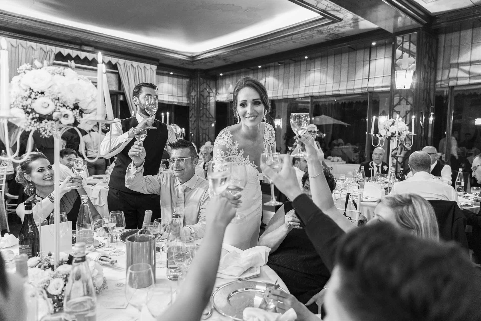 In bianco e nero, la sposa brinda in piedi tra gli amici