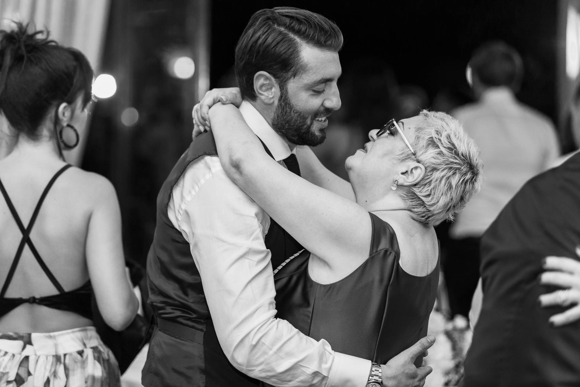 In bianco e nero, lo sposo abbraccia un'amica ridendo