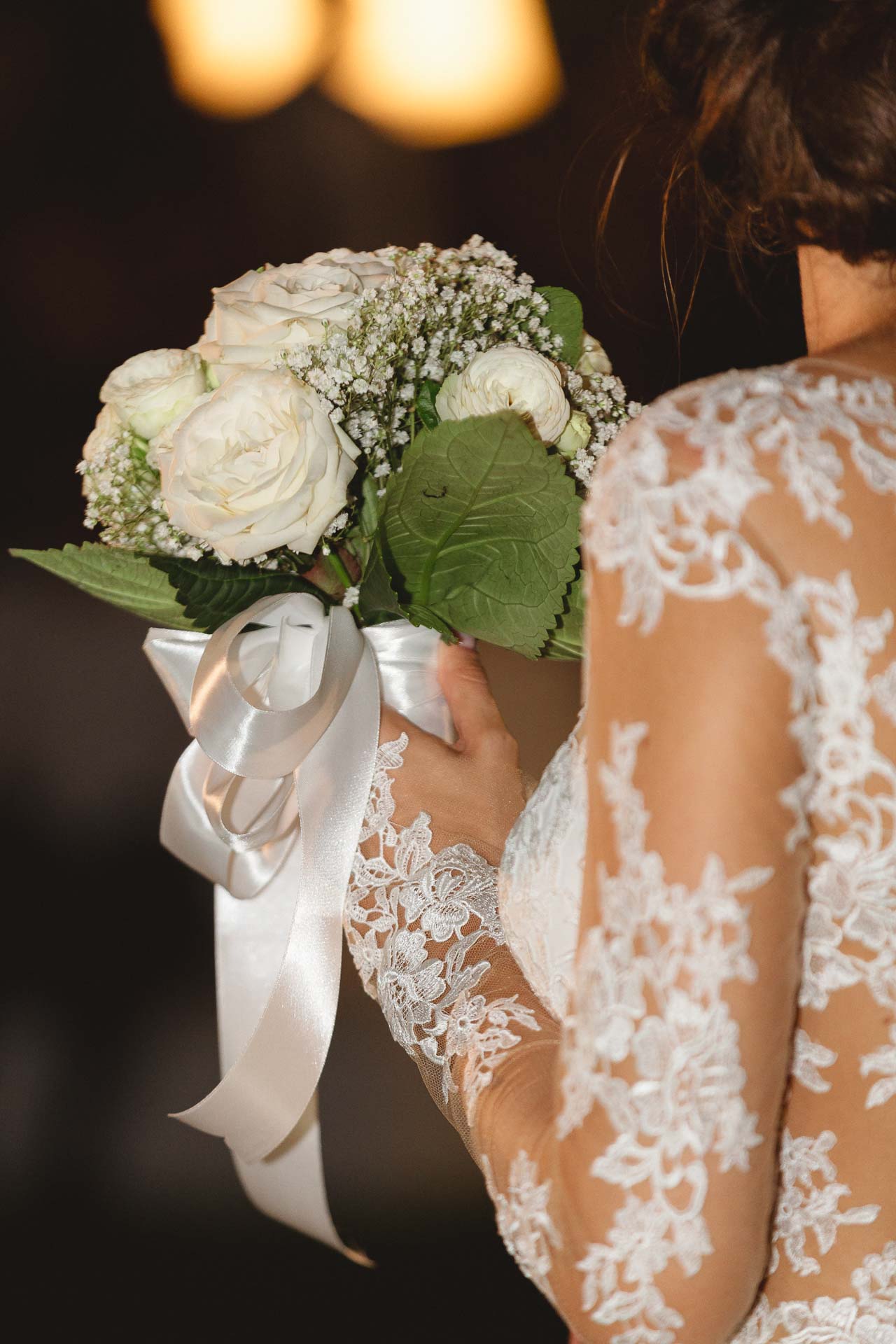 Il bouquet di rose bianche con il nastro, nelle mani della sposa