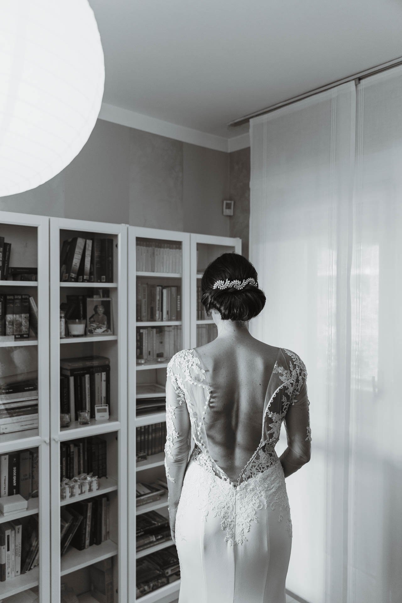 In bianco e nero, la schiena in pizzo dell'abito, davanti alla libreria