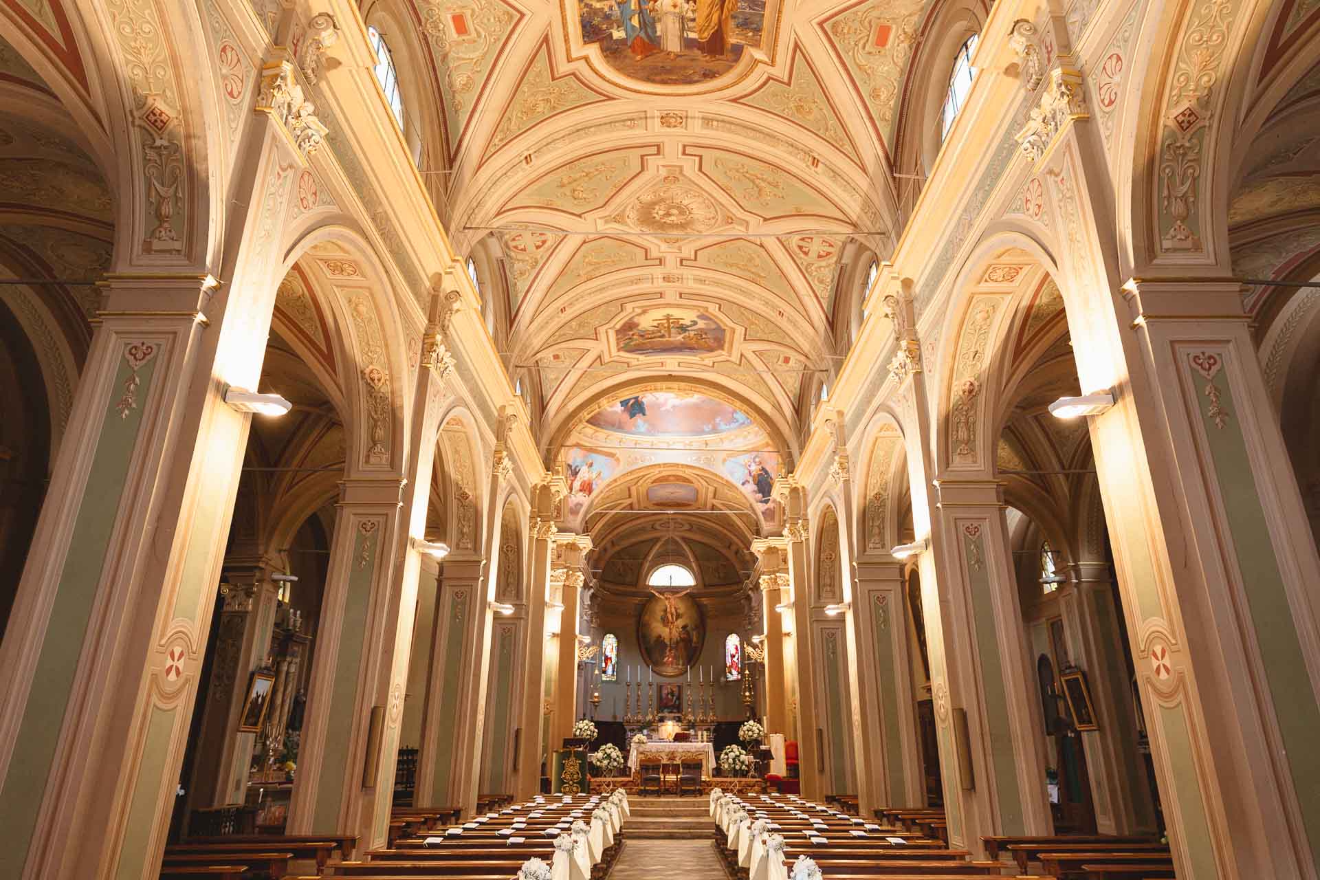 La navata della chiesa, con la volta affrescata e i nastri bianchi sulle panche