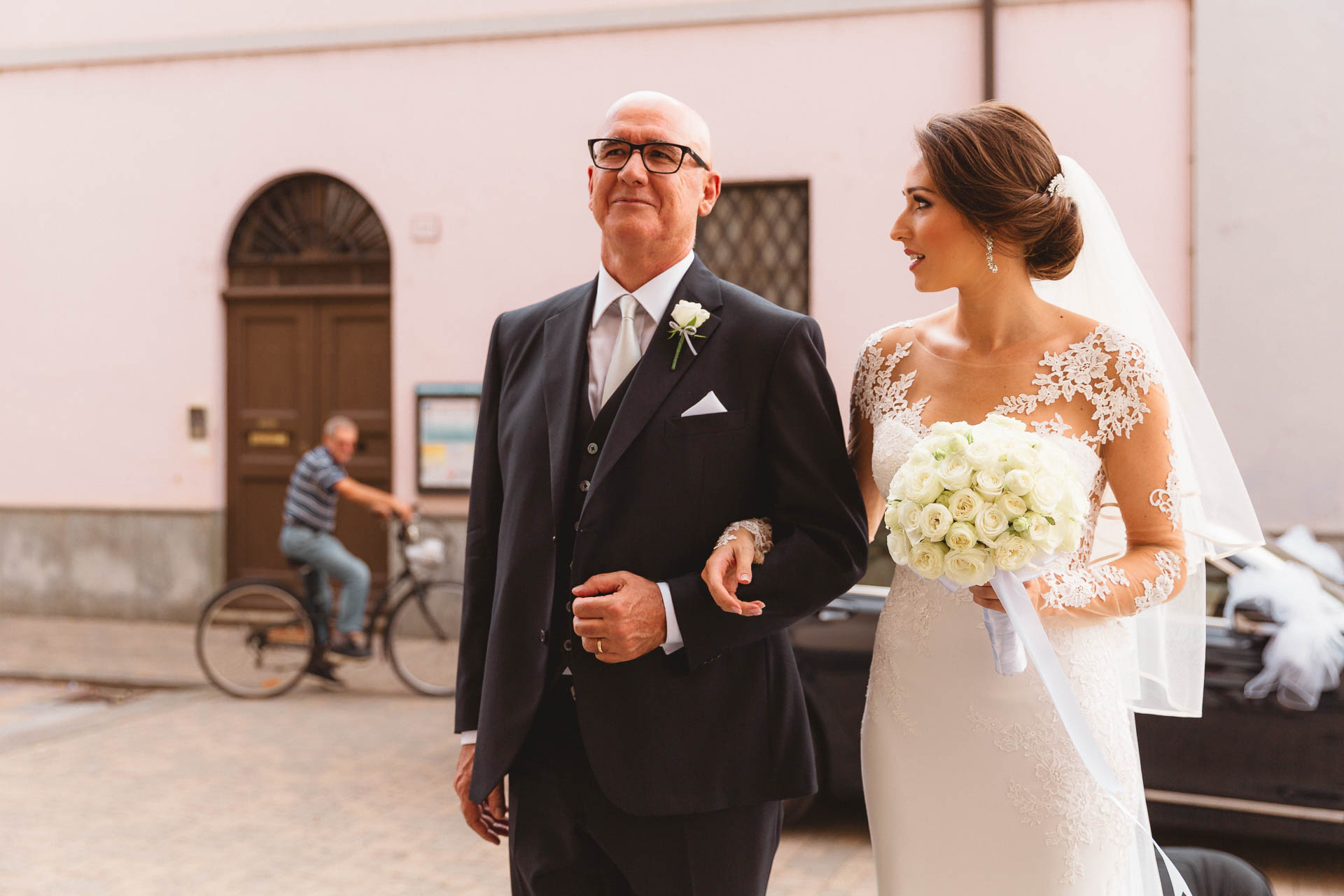 Il papà accompagna la sposa, con il bouquet di rose bianche