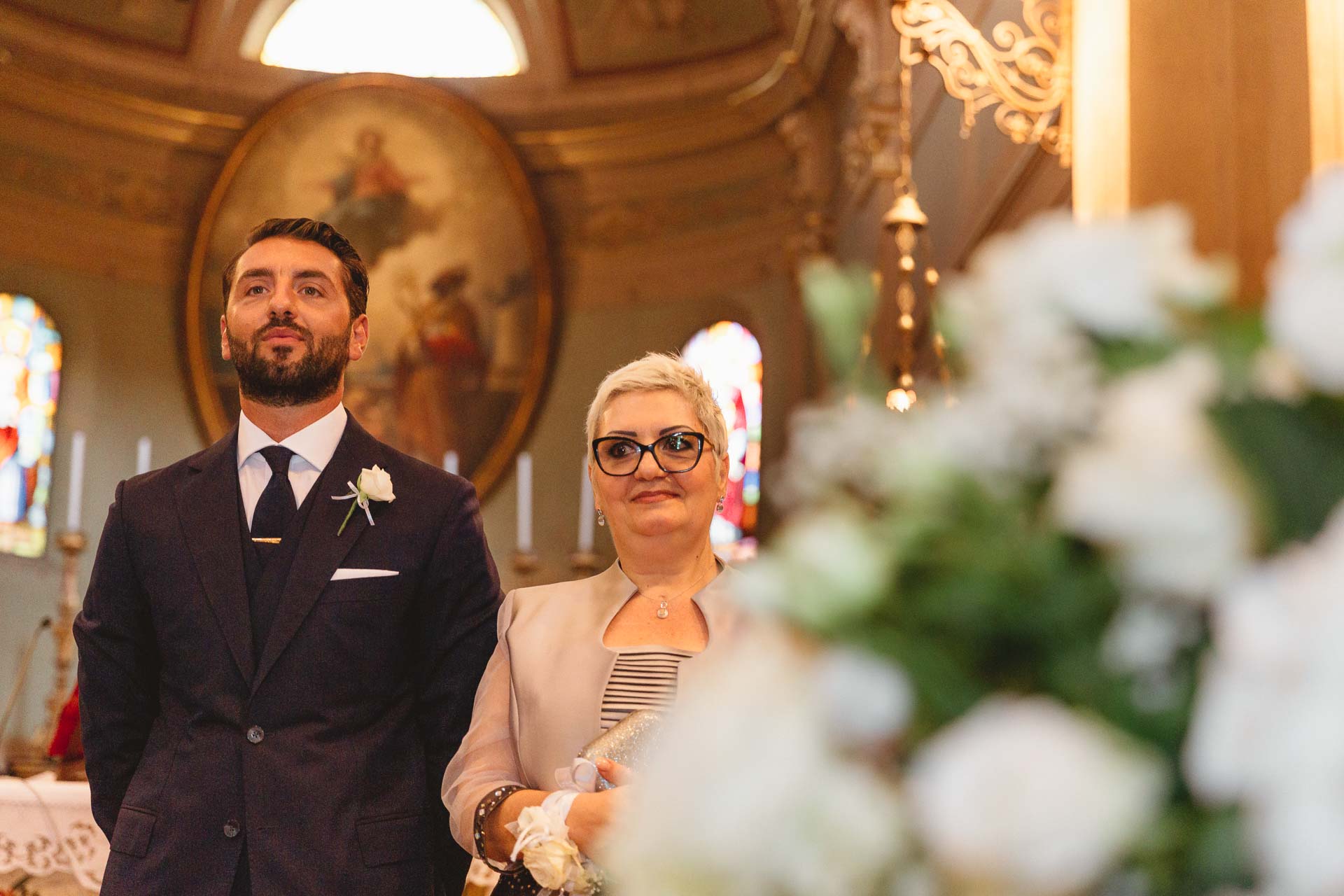 Lo sposo e la mamma aspettano all'altare, tra i fiori