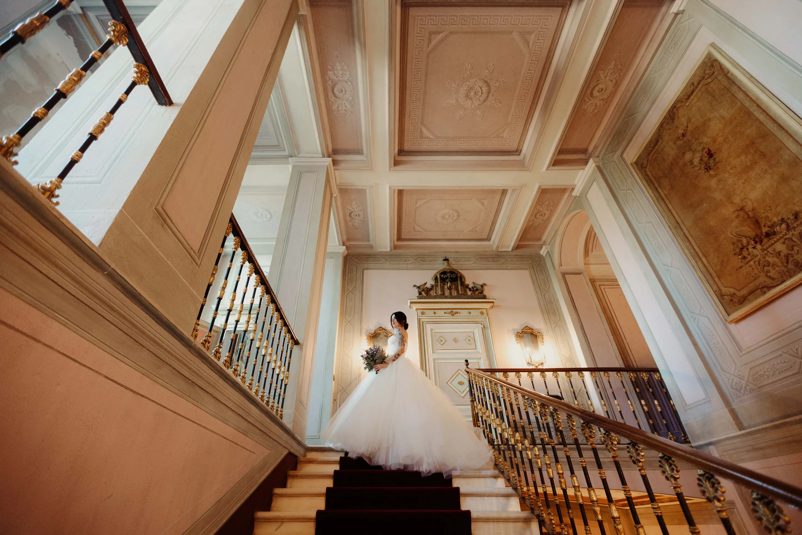 La sposa in cima allo scalone di Villa Cimena, sotto il soffitto a cassettoni